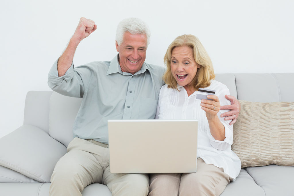 Cheerful senior couple doing online shopping through laptop and